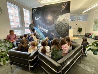A school class visiting ISSI and looking at the ISSI Mural asking questions about space science.